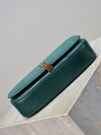 Teal leather handbag back view with curved flap and gold YSL clasp