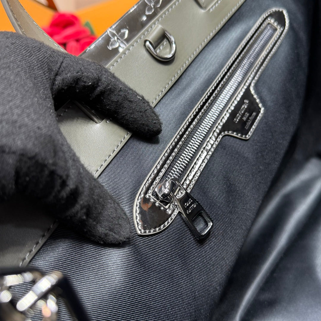 Men’s Louis Vuitton bag close-up of zipper pull and rectangular front logo patch.
