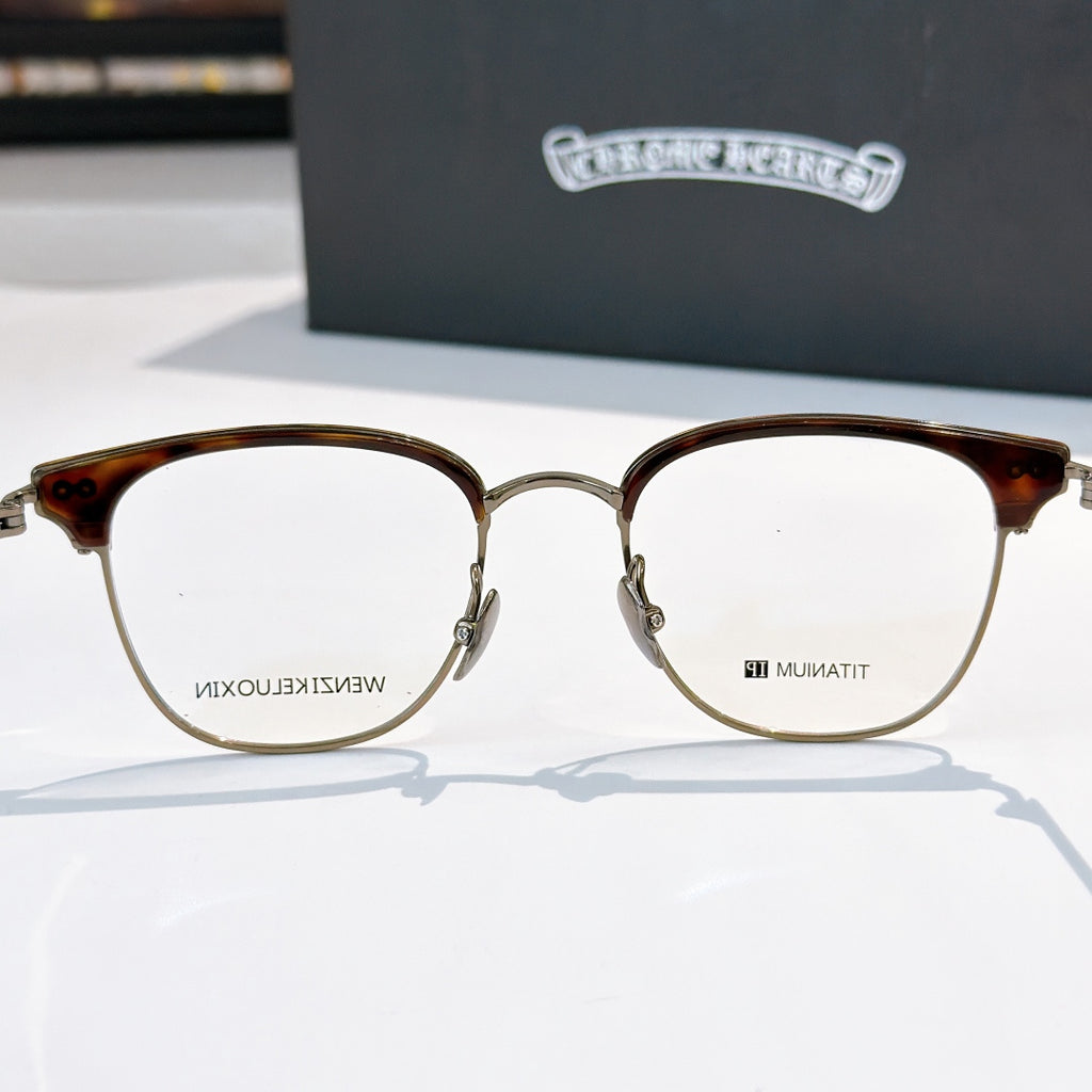 Gold-tone round eyeglass frames with clear lenses and dark tortoise accents