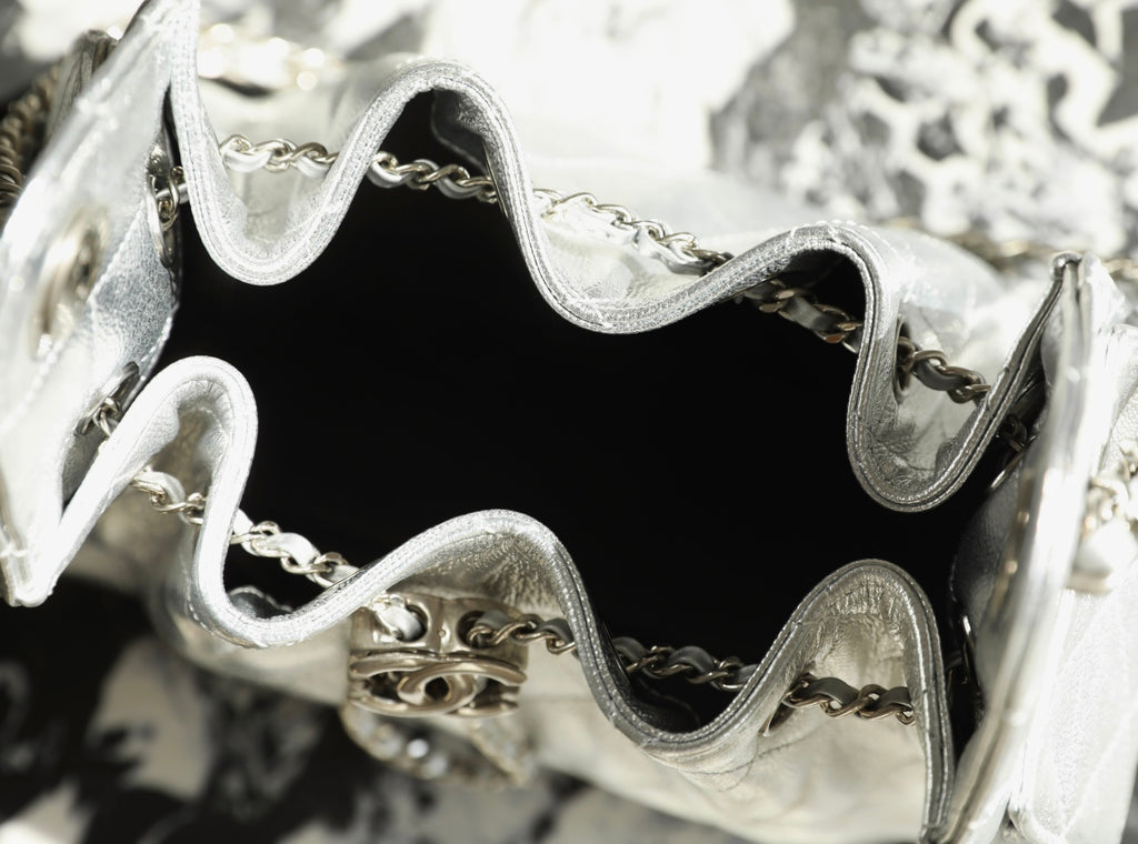 Silver handbag interior close-up with black lining and chain hardware