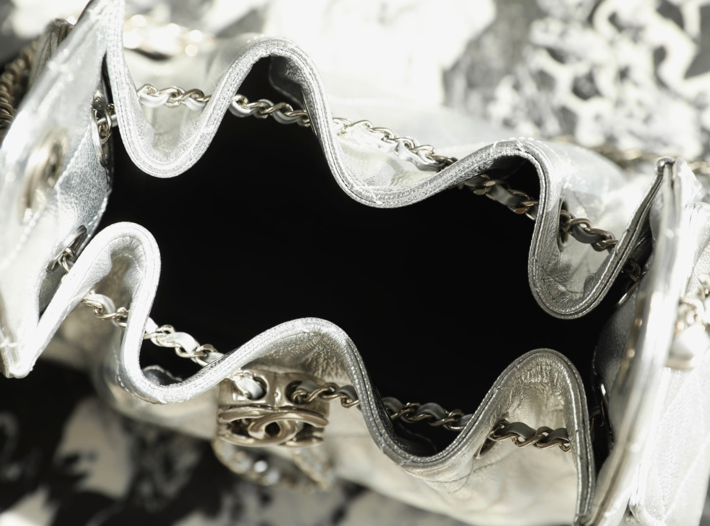 Silver handbag interior close-up with black lining and chain hardware