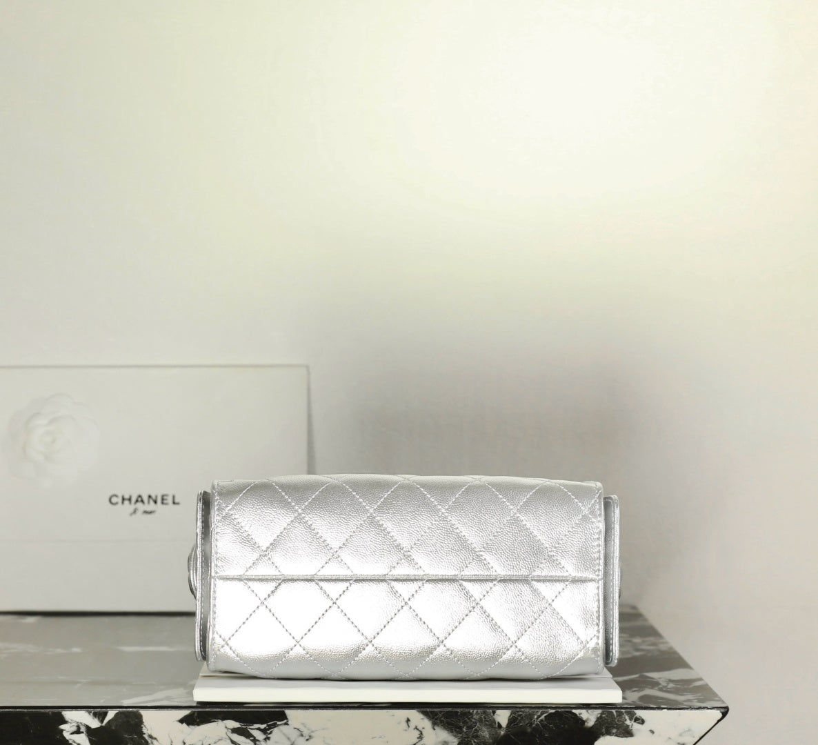 Silver quilted flap shoulder handbag with chain strap and clasp closure