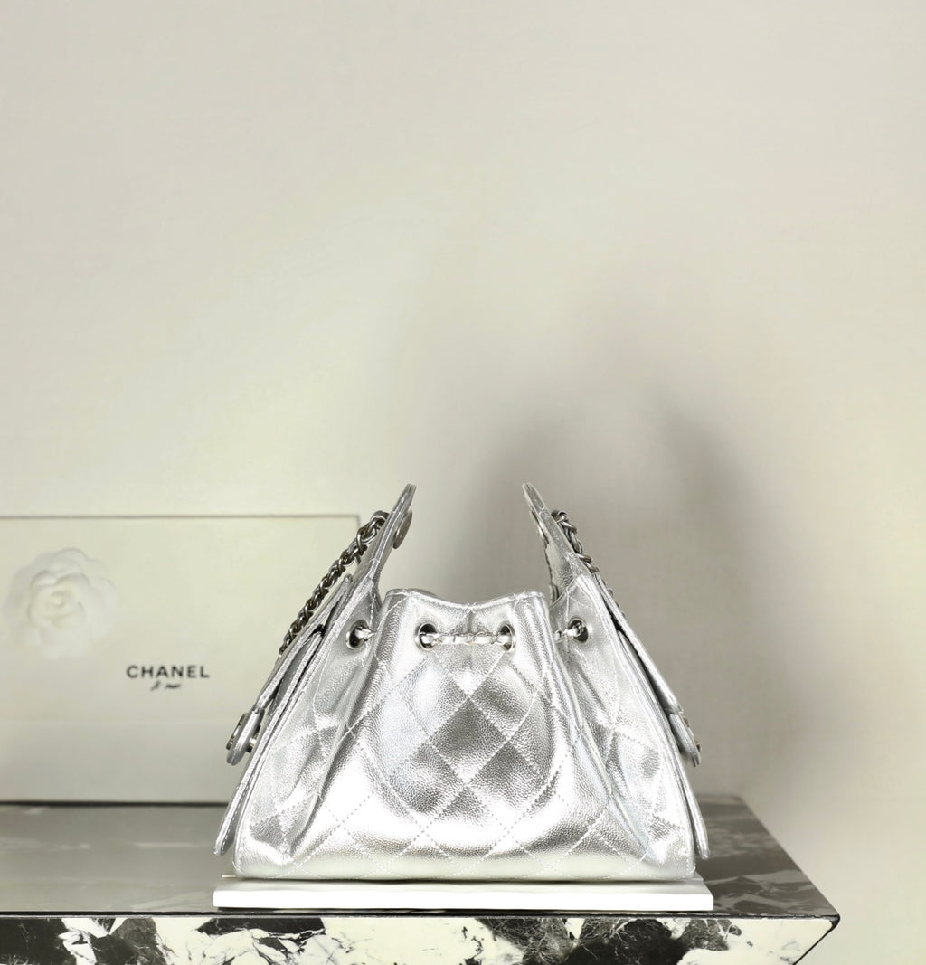 Silver metallic drawstring handbag with diamond quilting and chain shoulder straps