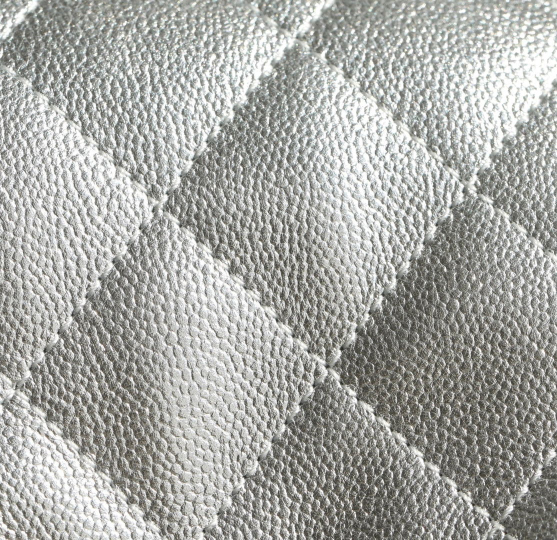 Silver quilted handbag leather texture close-up with diamond stitching