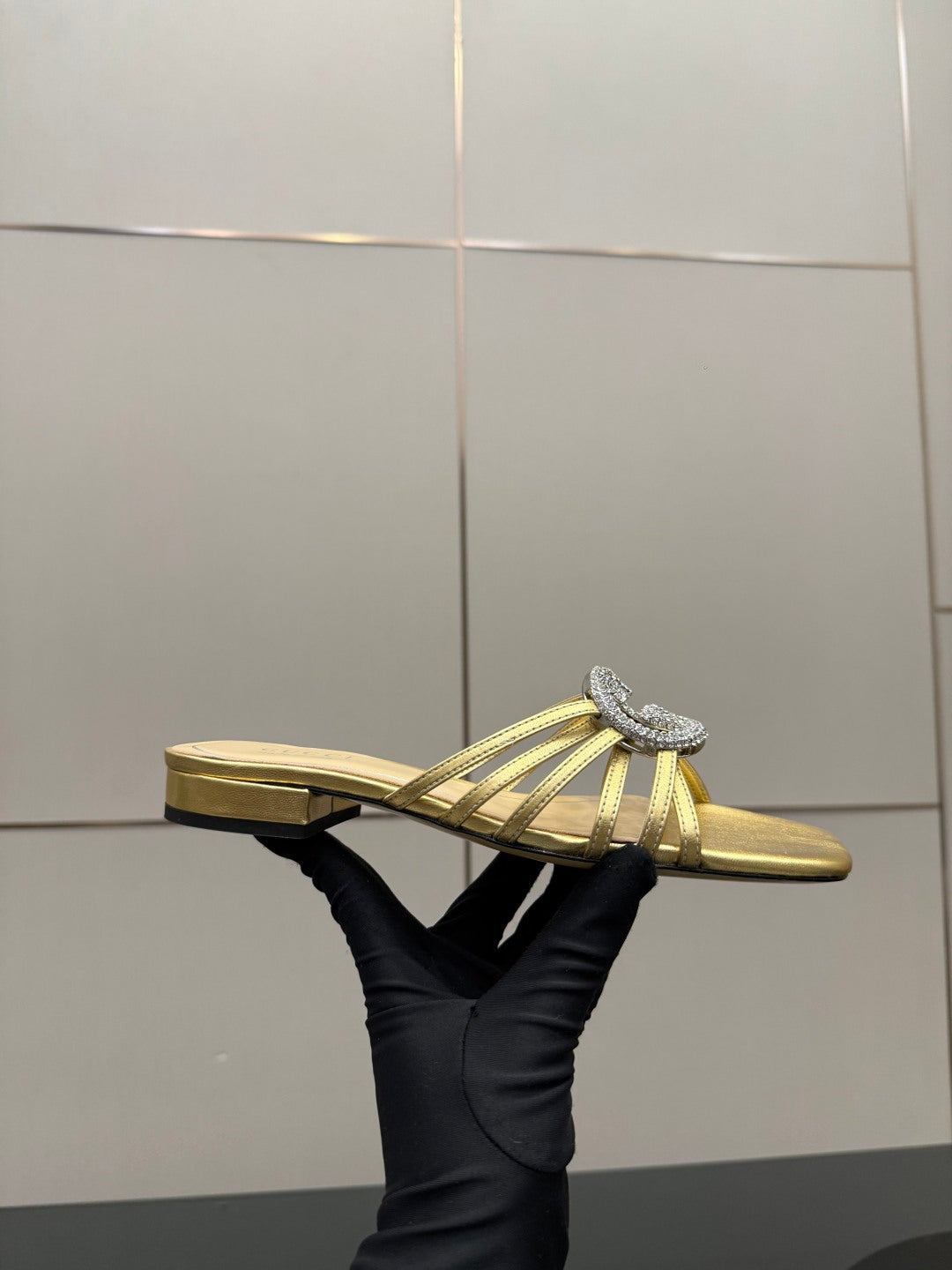 Gucci gold slide sandals with jeweled GG logo, low heel side view