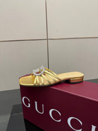 Gucci gold slide mule sandals with jeweled GG logo, front angle