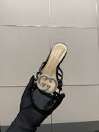 Gucci ladies black mule sandal held in hand with rhinestone GG emblem on upper