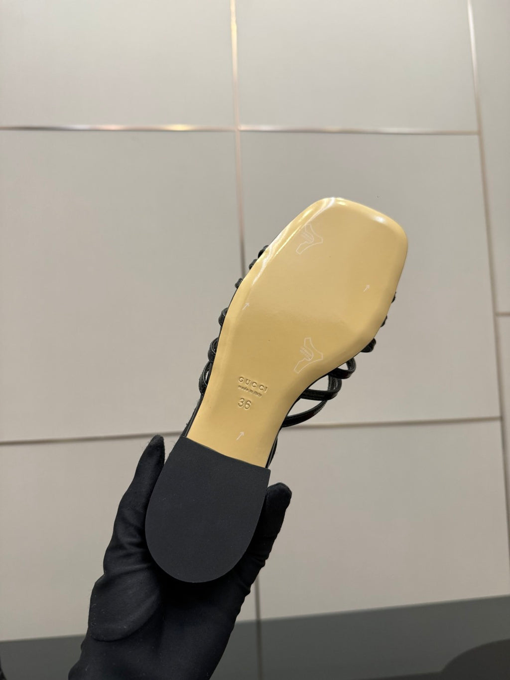 Gucci ladies black mule sandal outsole and yellow footbed held in hand