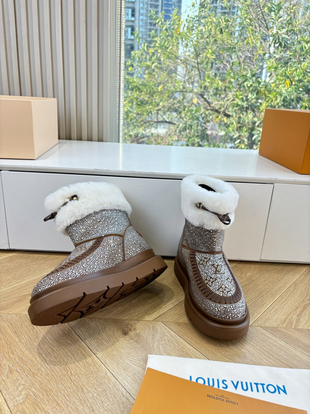 Brown glitter ankle boots with white shearling cuffs, set on indoor wooden floor