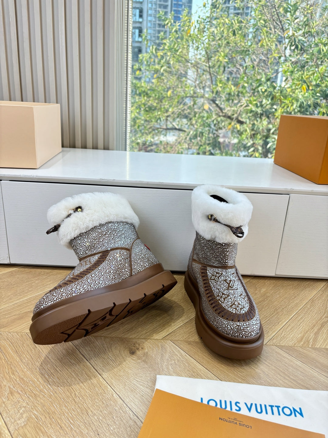 Brown glitter ankle boots with white shearling cuffs, set on indoor wooden floor