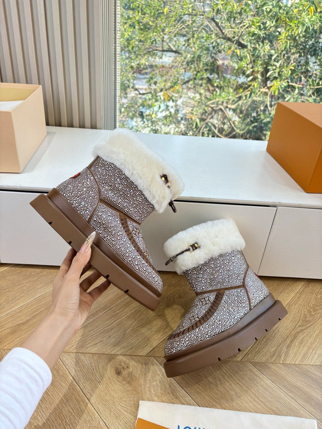 Brown glitter boots with white fur cuffs; hand holds one boot near the heel