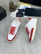 White and red low-top sneakers, angled side view with red laces and rubber sole.