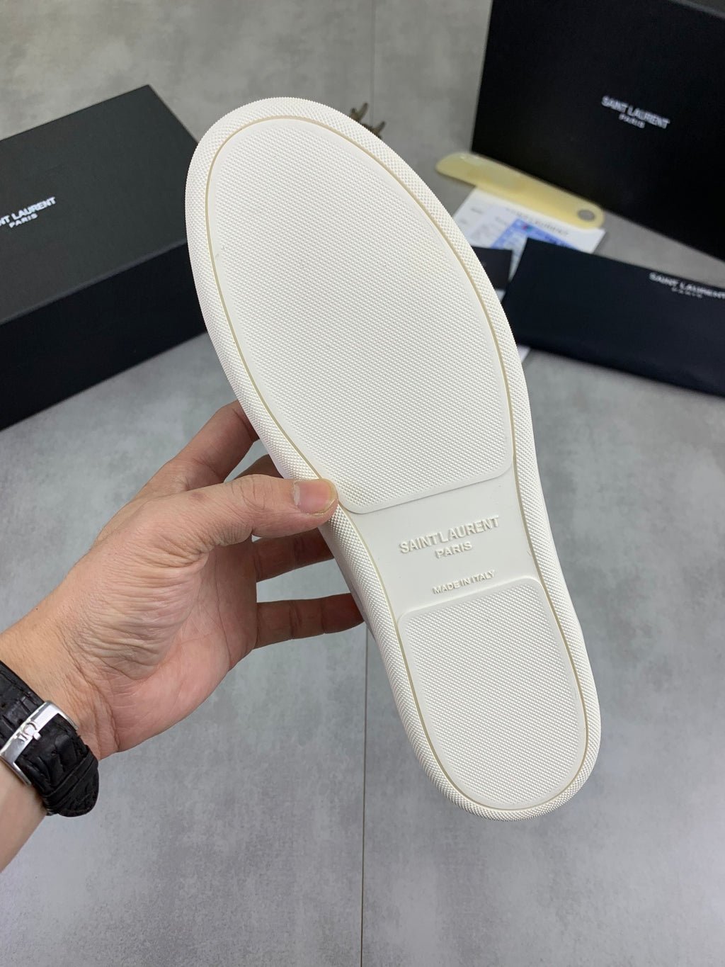 White sneaker outsole with textured grip tread, held in hand.