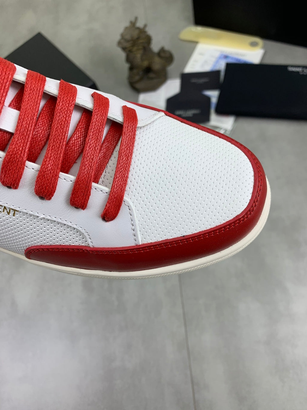 White and red sneaker toe with red laces and textured fabric vamp.