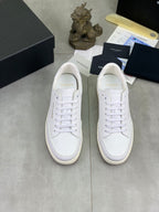 Pair of white lace-up sneakers with sidewall stitch detail and beige-toned rubber sole