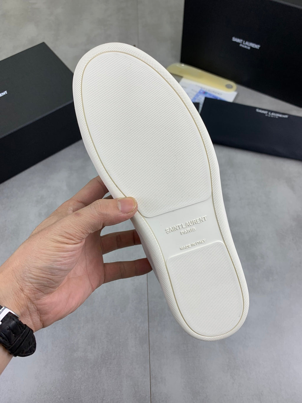 White sneaker outsole underside with textured tread and beige rubber edge