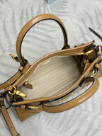 Tan leather tote bag open top view with gold zipper and curved handle