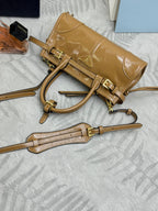 Tan leather tote bag detail with gold buckles and detachable shoulder strap on side