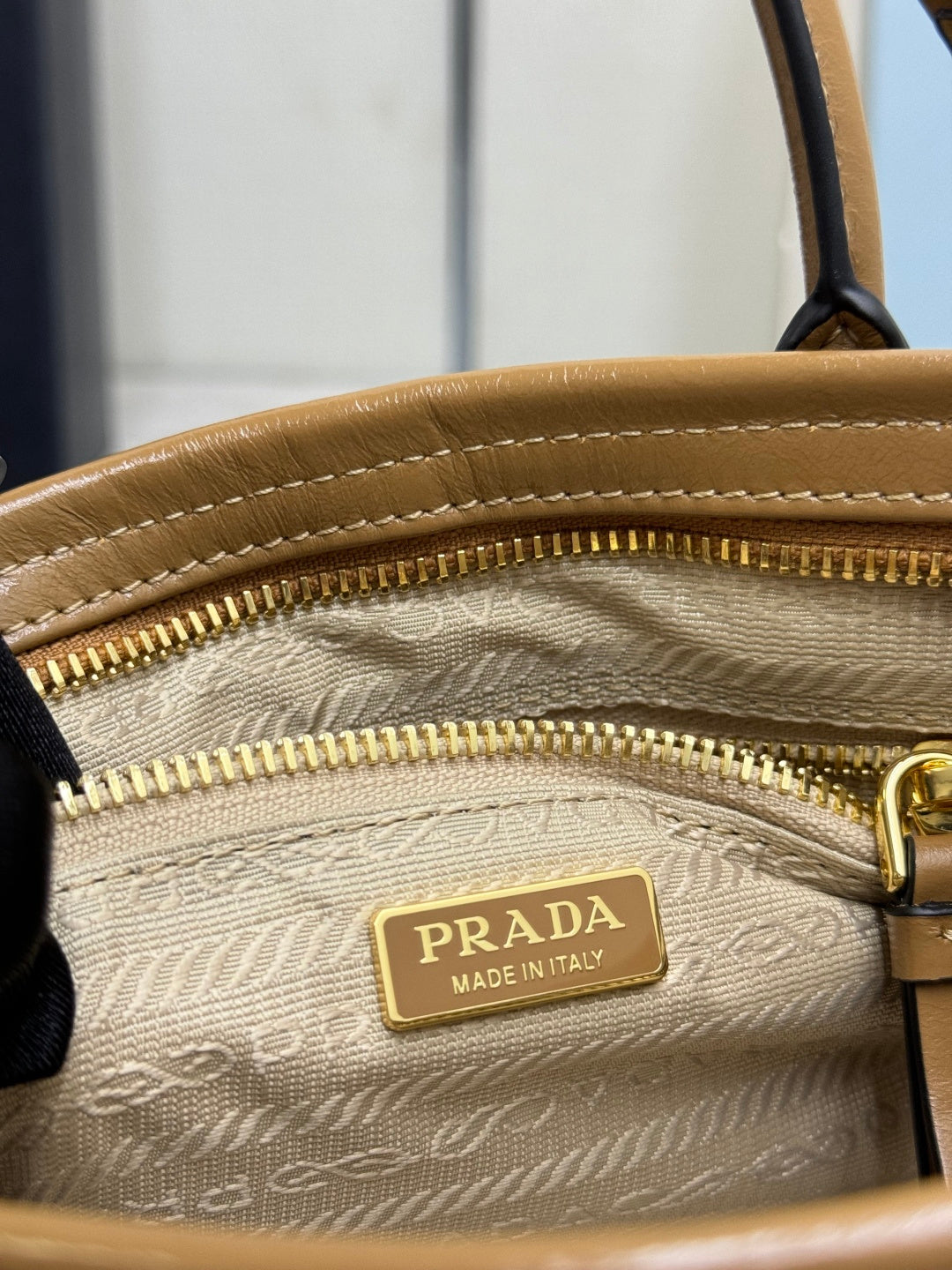 Tan leather zipper pocket with Prada Made in Italy logo plaque and gold zipper pull