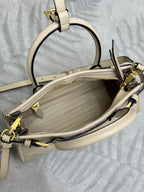 Cream leather Prada handbag interior view with top opening, zipper, and shoulder strap