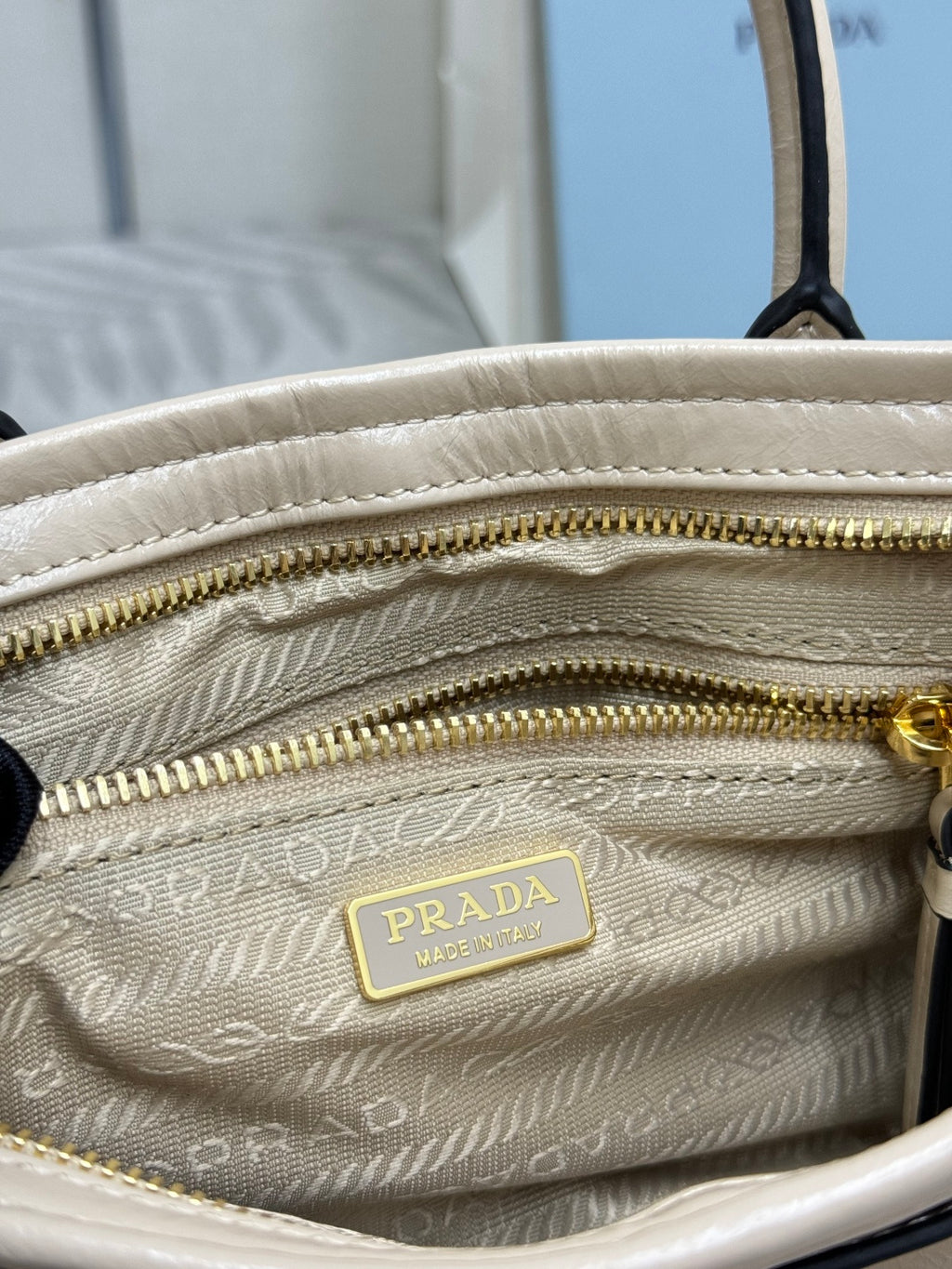 Cream leather Prada mini bag interior with lined pattern and gold-tone zipper pull