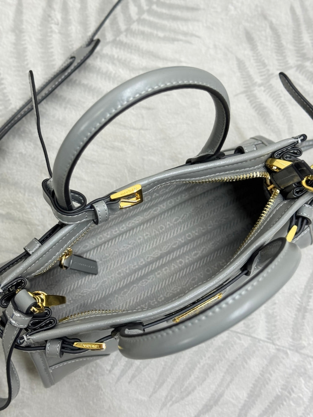 Light gray leather handbag interior top view with rolled handles and zipper hardware