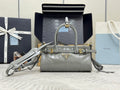 Light gray leather handbag with top handles, logo plaque, and crossbody strap