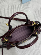 Burgundy leather handbag with open top and patterned logo lining, showing dual handles.