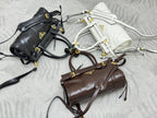 Prada mini handbags laid flat in black, white, and brown with strap hardware