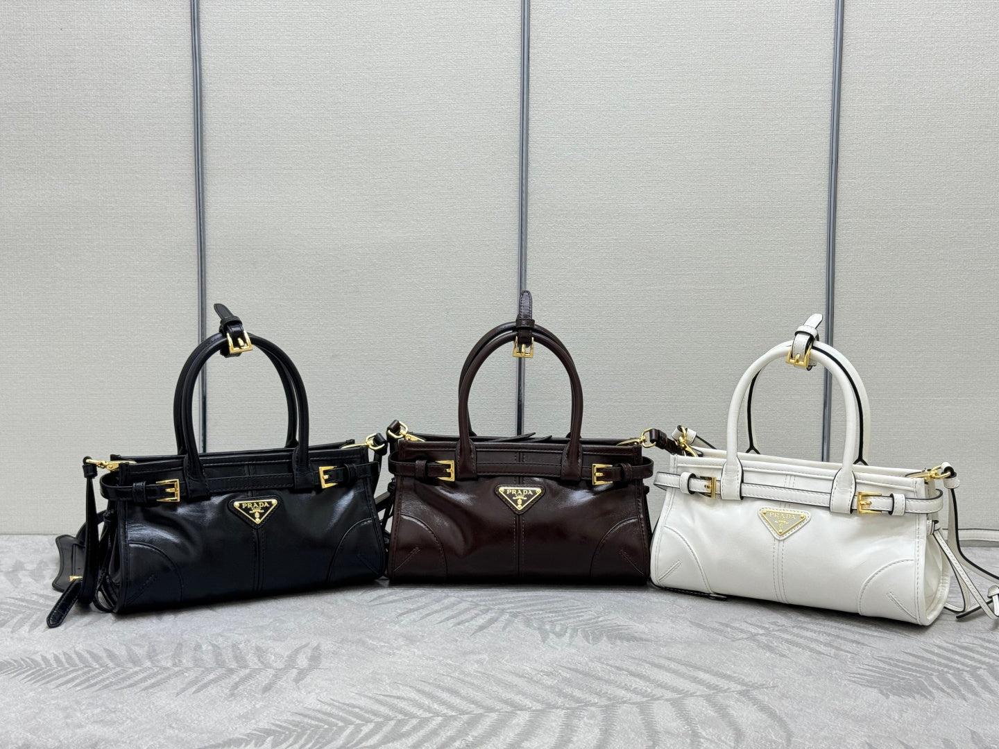 Prada handbags in black, dark brown, and white with top handles and shoulder straps
