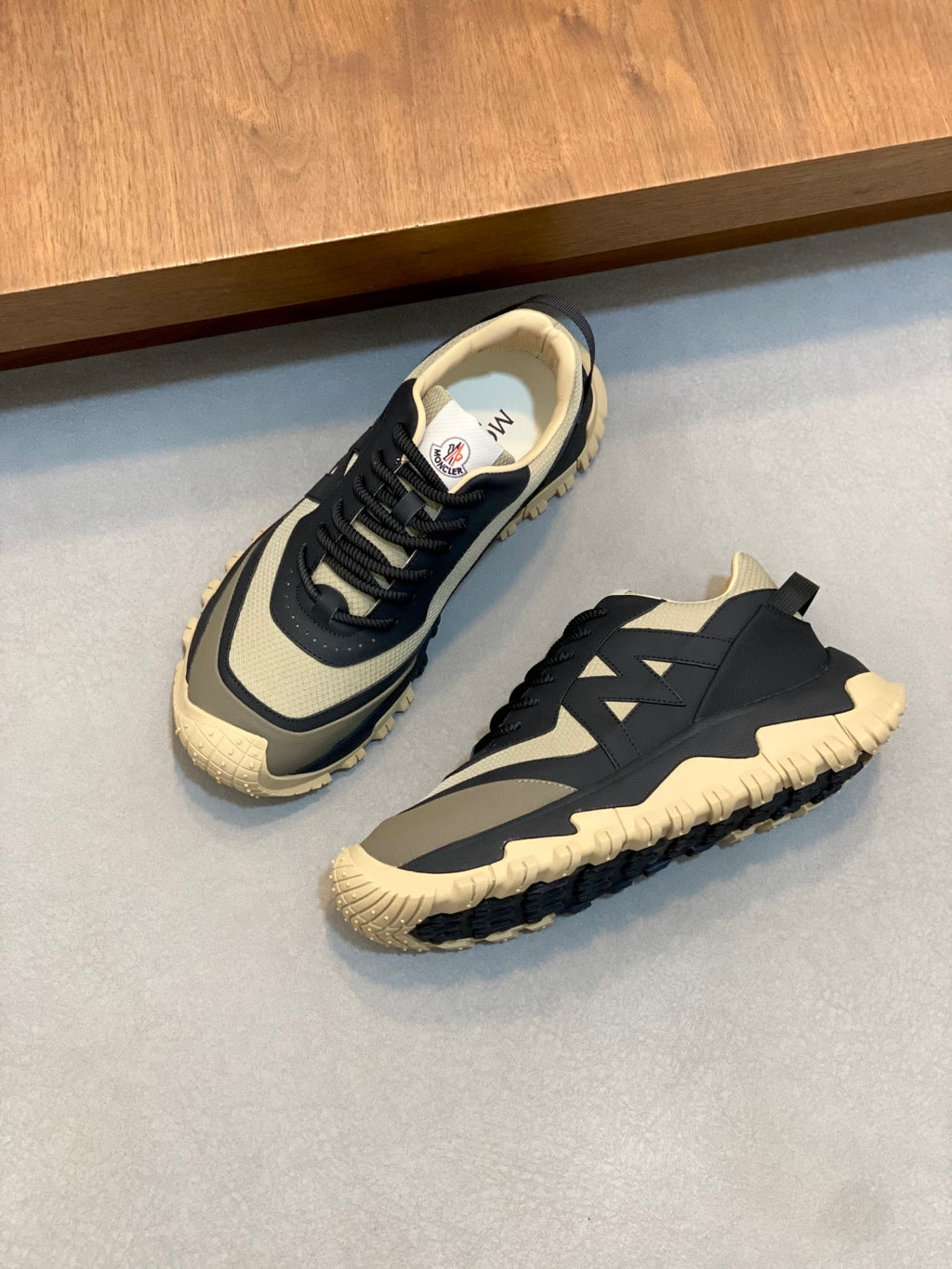 Moncler sneakers shown side by side in dark navy with beige midsoles and treaded sole