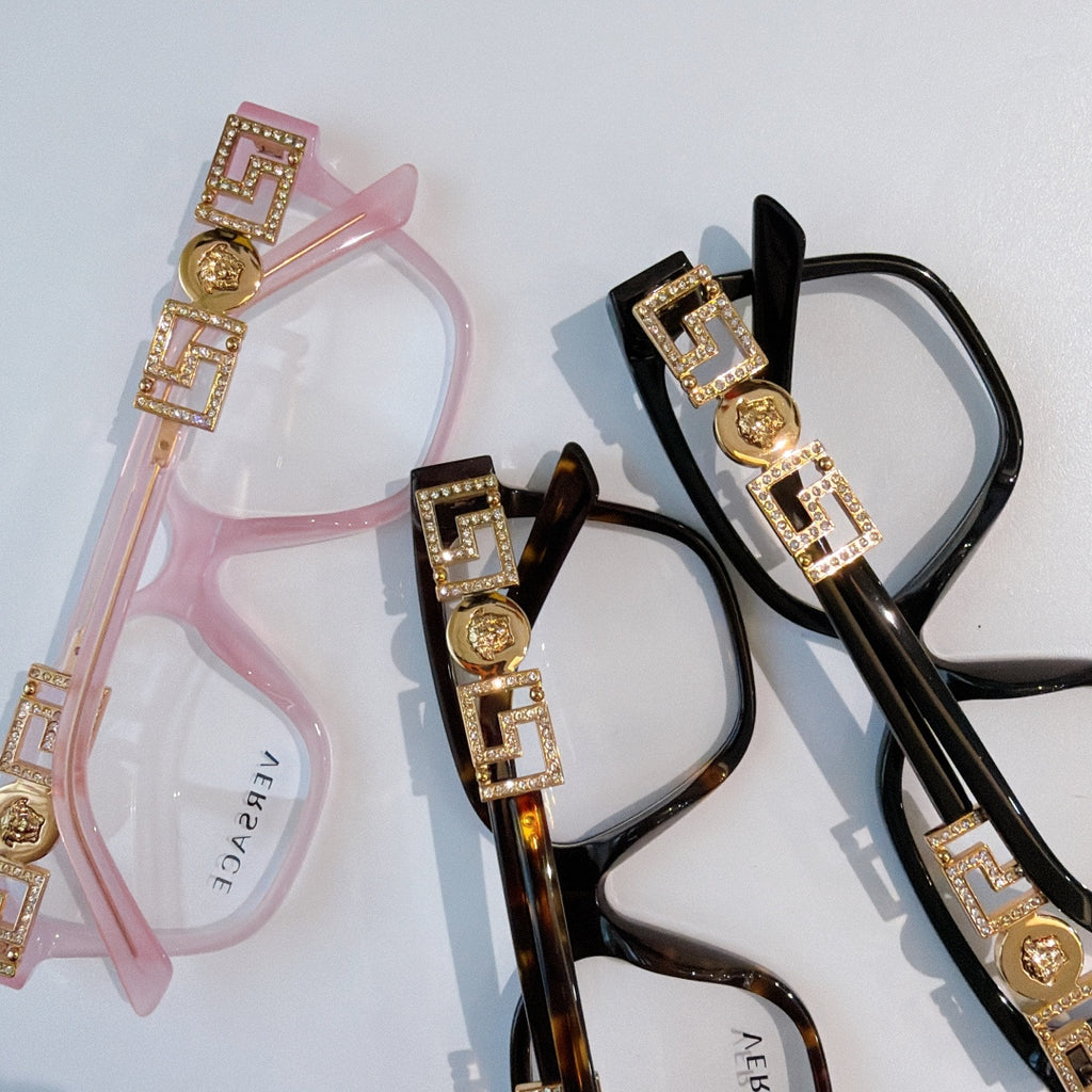Pink and black eyeglasses with gold logo temple details and clear lenses