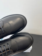 Dark leather lace-up shoes with rounded toe and patterned collar trim, close-up