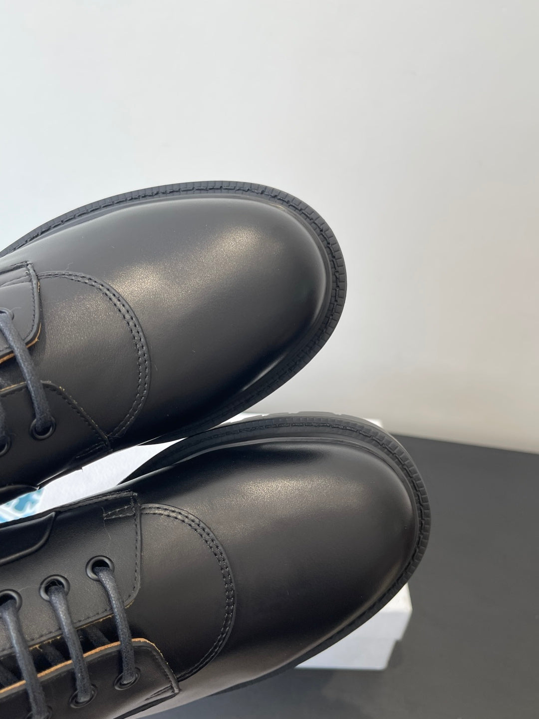 Dark leather lace-up shoes with rounded toe and patterned collar trim, close-up