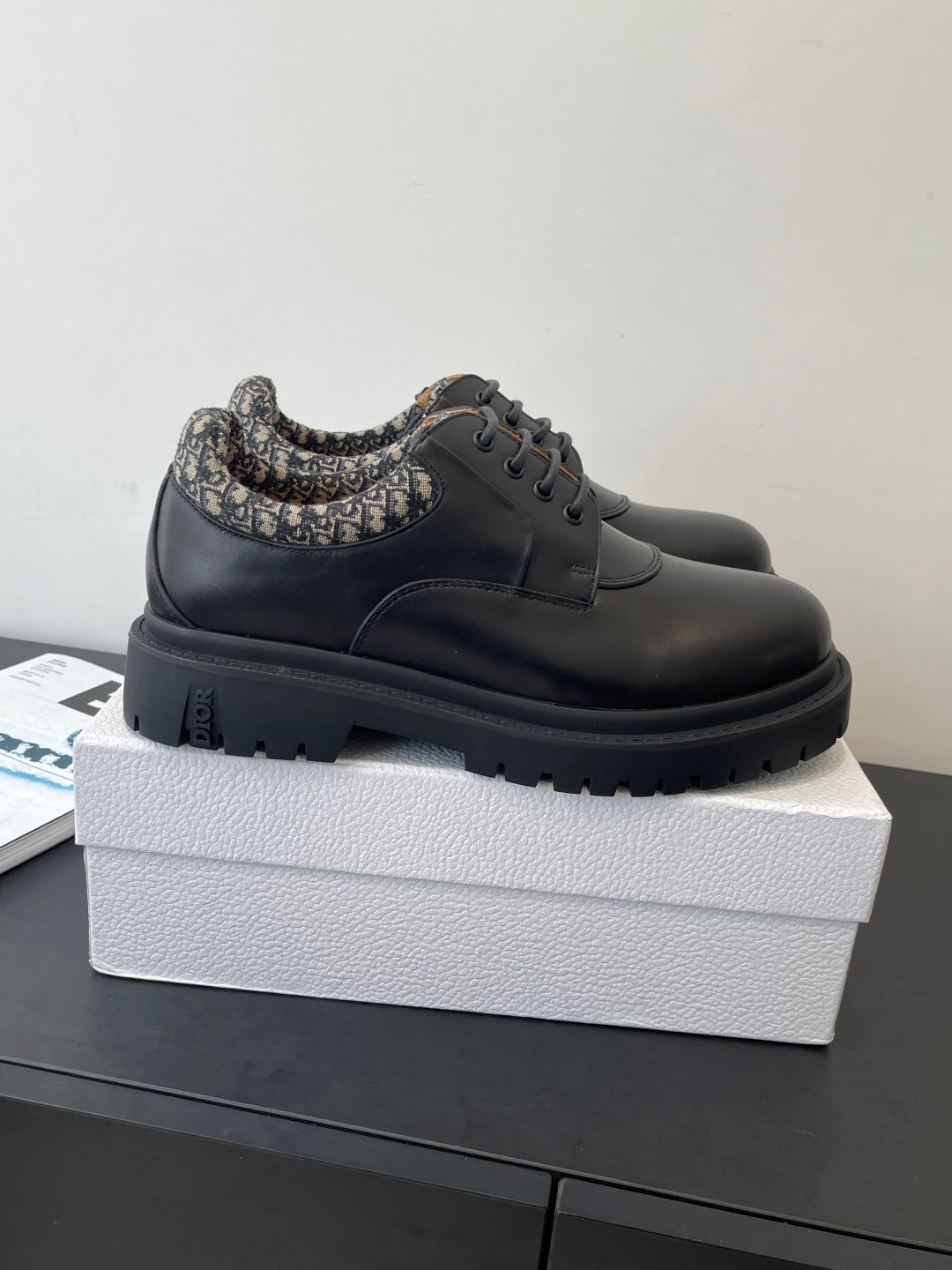 Dior lace-up shoes in dark leather with patterned collar, side view on box