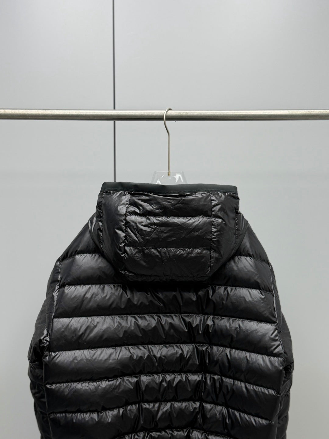 Long Moncler puffer jacket back view, black with hood and horizontal quilted panels