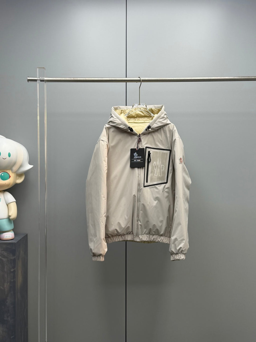 Light beige long zip-up puffer jacket with hood, ribbed cuffs, and front tags