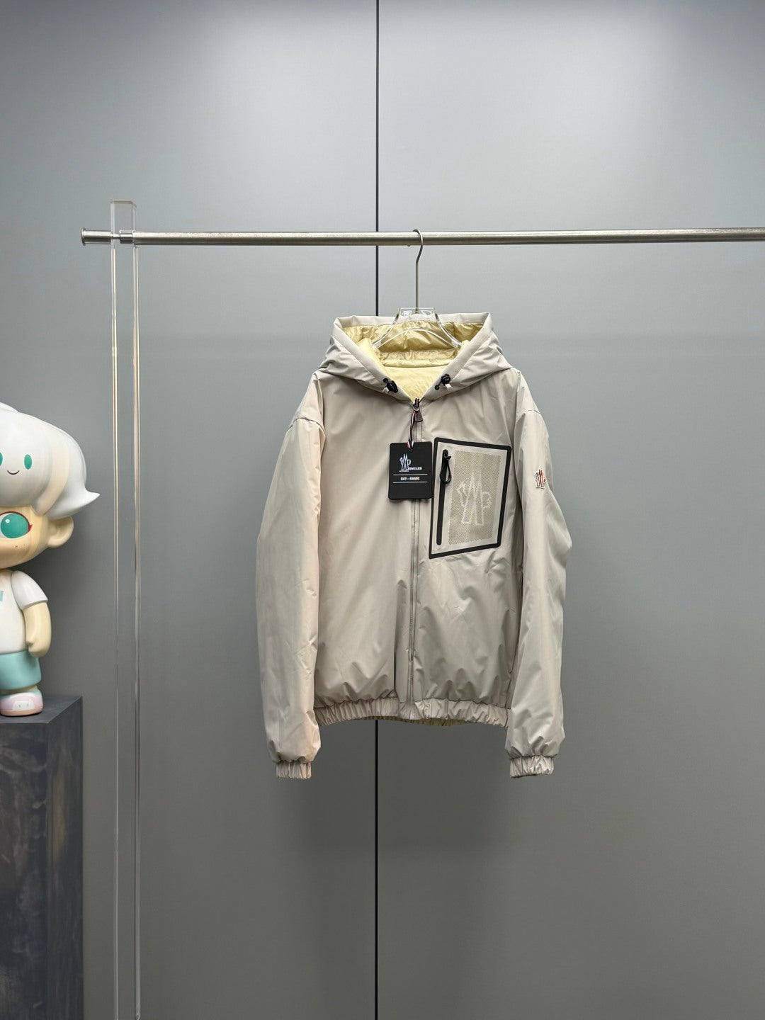 Light beige long zip-up puffer jacket with hood, ribbed cuffs, and front tags
