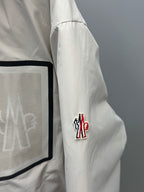 White-beige long puffer jacket sleeve with red-blue logo patch detail