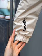 Light beige puffer jacket sleeve cuff with vertical "DAYANAY" text