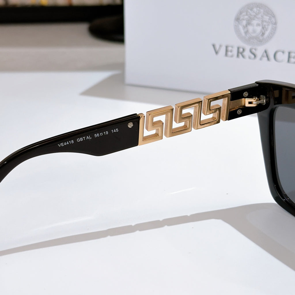 Black sunglasses with gold patterned temple bar and dark tinted lenses