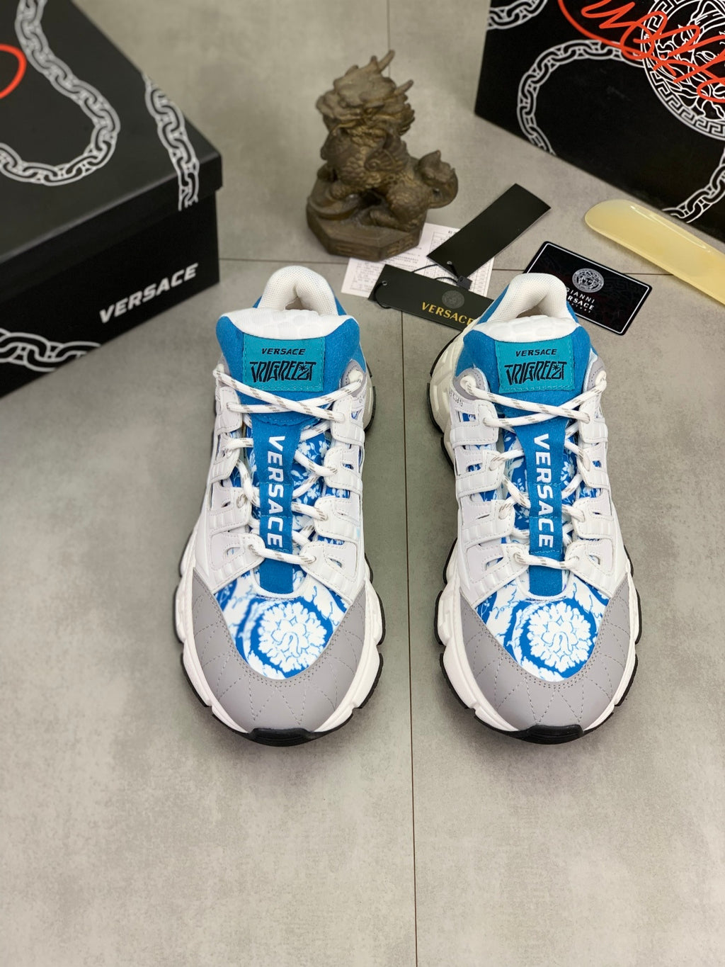 Pair of white and blue lace-up sneakers with blue logo print on toe and tongue.