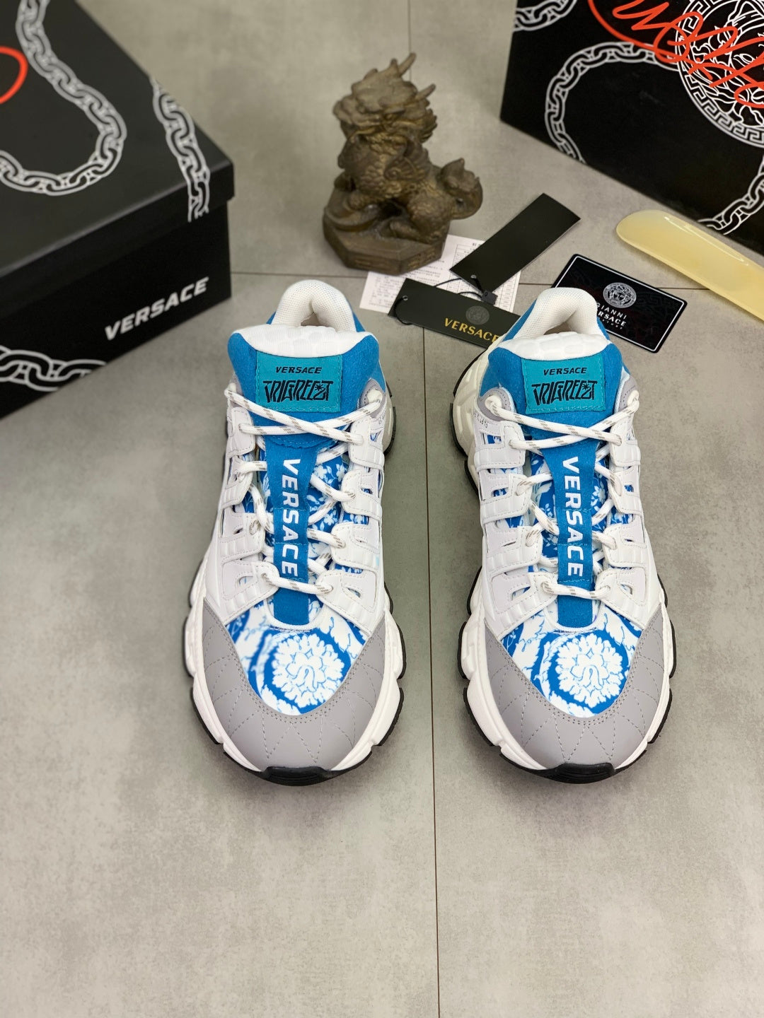 Pair of white and blue lace-up sneakers with blue logo print on toe and tongue.