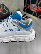 White sneaker with blue panel trim, blue laces, and chunky tread sole.