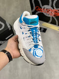 White and blue lace-up sneakers with blue logo patch and chunky tread sole.