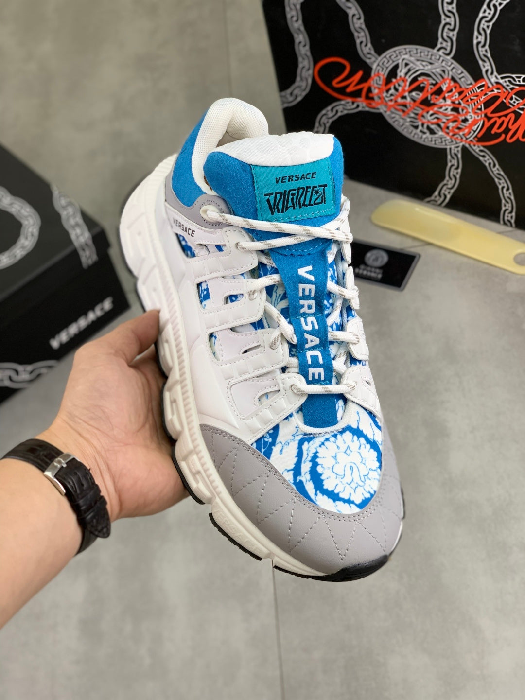 White and blue lace-up sneakers with blue logo patch and chunky tread sole.