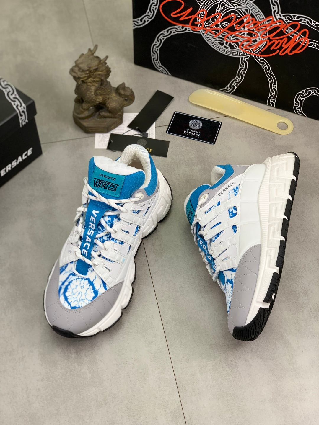 White and blue lace-up sneakers with thick tread sole and blue logo panel.