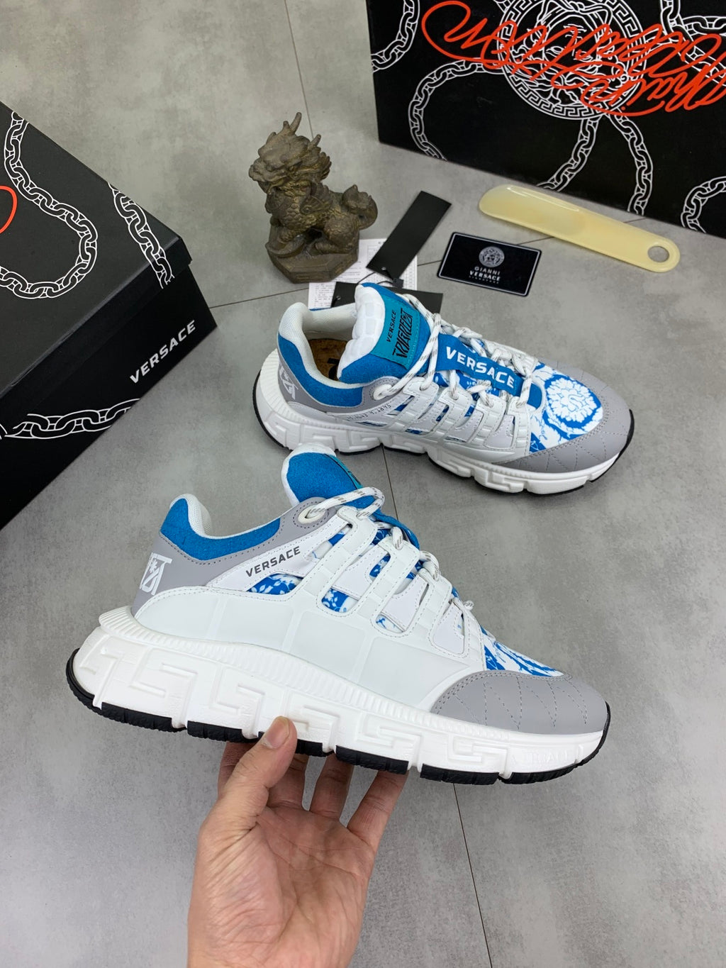 White and blue lace-up sneakers with grippy sole and blue logo detail on upper.