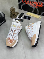 White low-top sneakers with tan heel panel and brown floral design on the toe