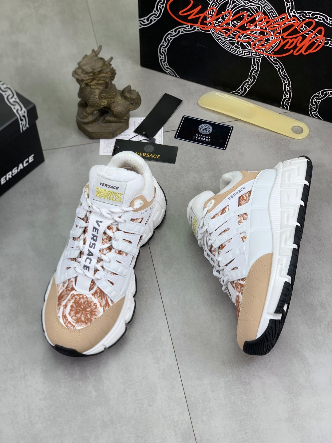 White low-top sneakers with tan heel panel and brown floral design on the toe
